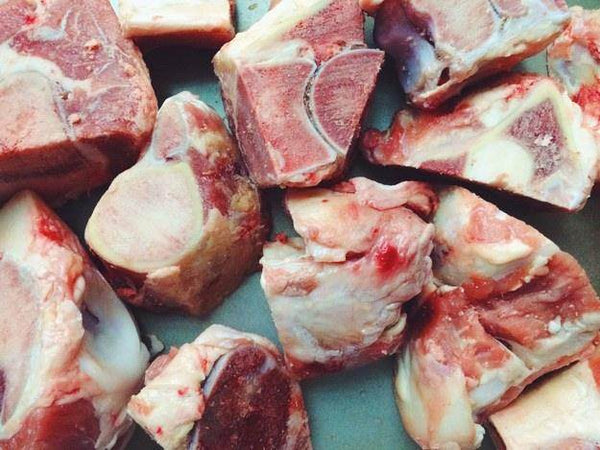 Raw beef bones cut into chunks with visible marrow and fat, ideal for cooking or broth