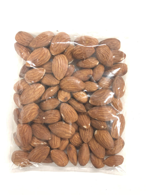 Transparent plastic bag filled with raw brown whole almonds on white background