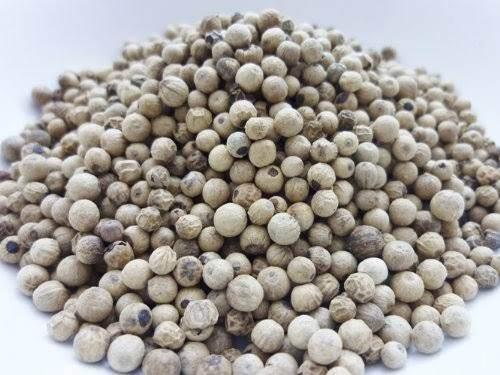 Close-up of a pile of white peppercorns on a white background, showing their round texture