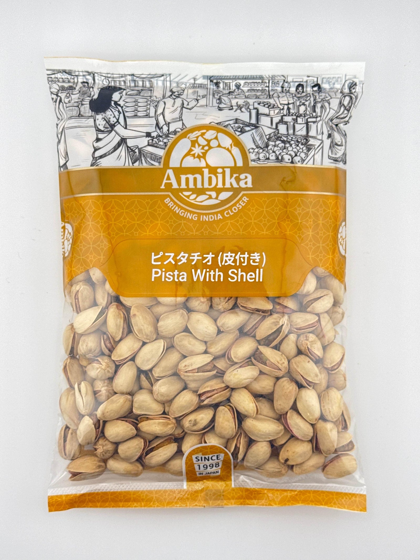 Ambika brand packaged pistachios with shells, featuring an Indian market illustration on top