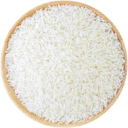 Close-up of white uncooked rice grains evenly spread in a round wooden bowl