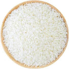 Close-up of white uncooked rice grains evenly spread in a round wooden bowl