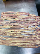 Strips of raw animal intestines with fat on a metal surface, prepared for cooking or processing