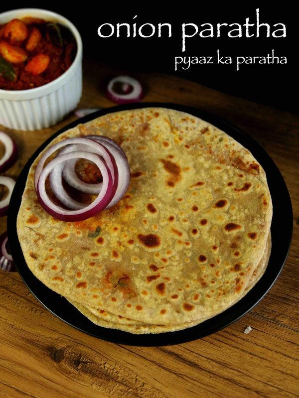 Onion paratha served on a black plate with raw onion rings and a side of spicy curry in a white bowl