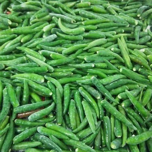 Close-up of fresh green chili peppers piled together, highlighting their vibrant color and texture