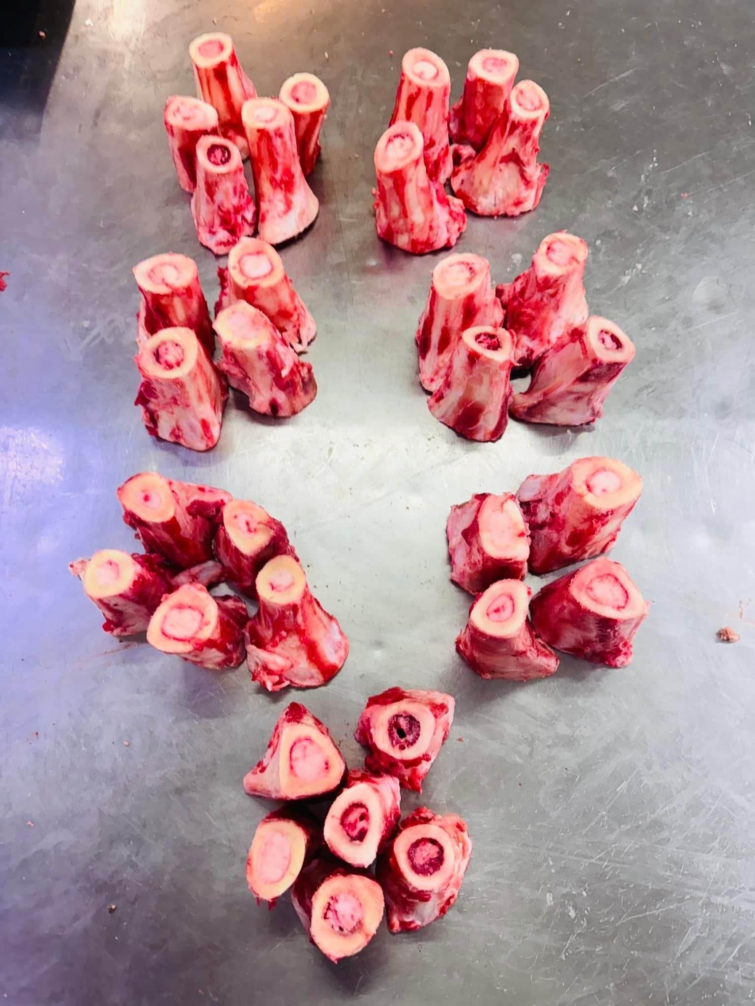 Raw beef bone marrow segments arranged on a stainless steel surface