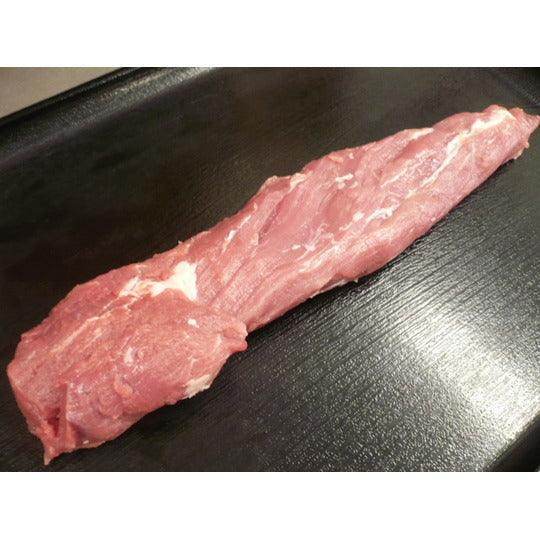 raw pork tenderloin on black textured cutting board close-up