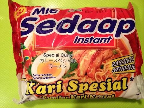 Mie Sedaap Instant Kari Spesial instant noodle package with special curry flavor and shrimp on a green background
