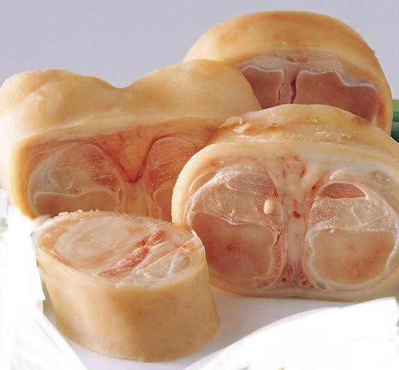 Raw sliced beef marrow bones with rich bone marrow visible inside on a white surface
