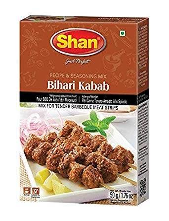 Shan Bihari Kabab spice mix box with grilled meat skewers, lemon wedges, and mint garnish on white plate