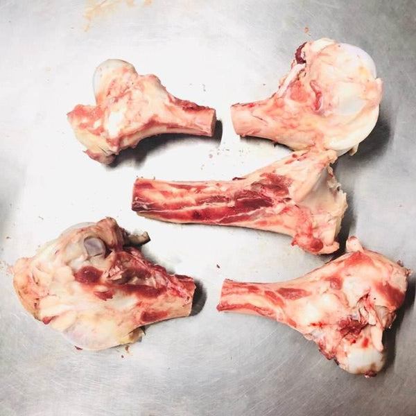 Raw goat head bones with meat on a metal surface, fresh butchered animal parts