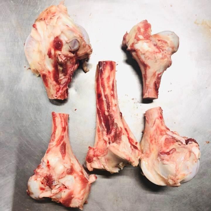 Raw beef marrow bones with meat and fat on a metal surface for cooking or broth