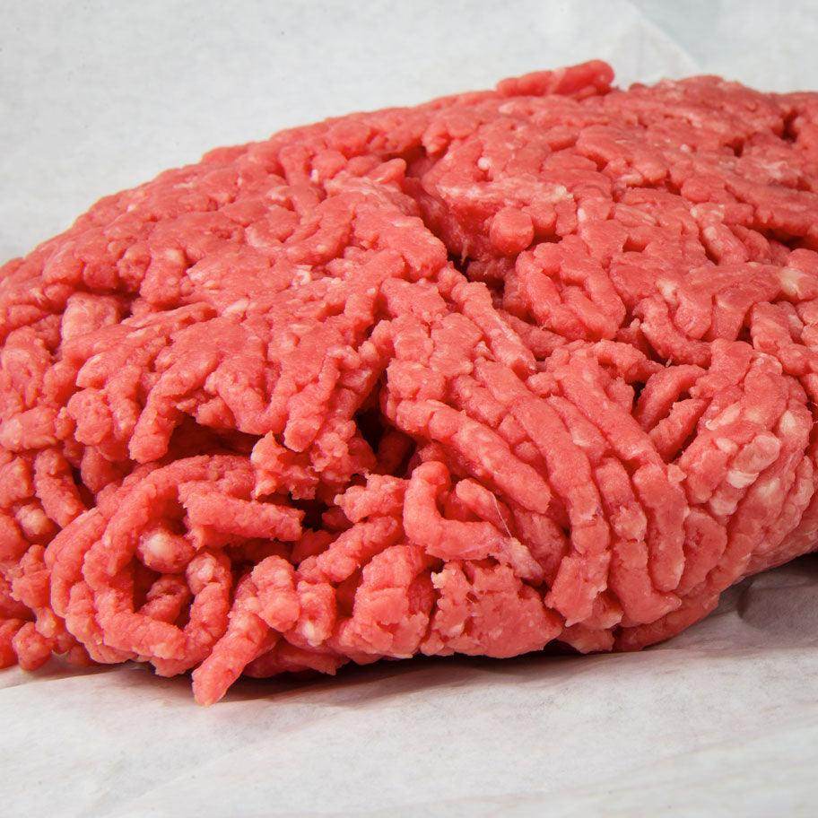 Fresh raw ground beef on white butcher paper, close-up detail of minced meat texture