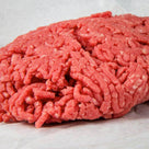 Fresh raw ground beef on white butcher paper, close-up detail of minced meat texture