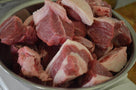 Raw beef meat chunks with fat in a metal bowl, ready for cooking or stew