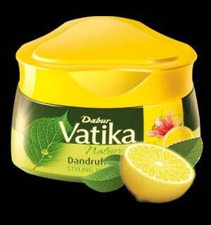 Dabur Vatika Dandruff Guard Hair Cream container with lemon and herbal leaves on black background