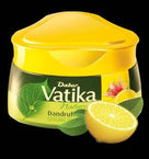 Dabur Vatika Dandruff Guard Hair Cream container with lemon and herbal leaves on black background
