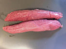 Two raw pink pork tenderloin pieces on a dark cutting board ready for cooking