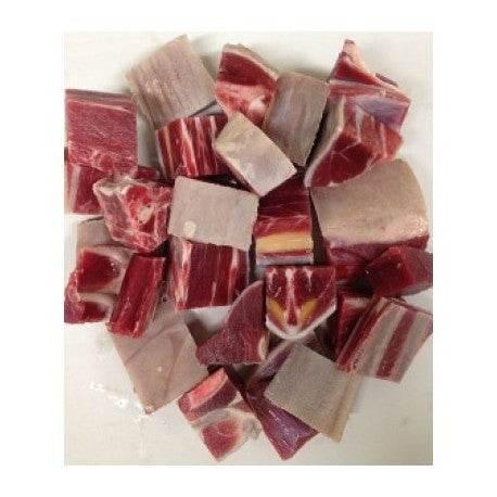 Raw goat meat chunks with fat, ready for cooking, on a white background