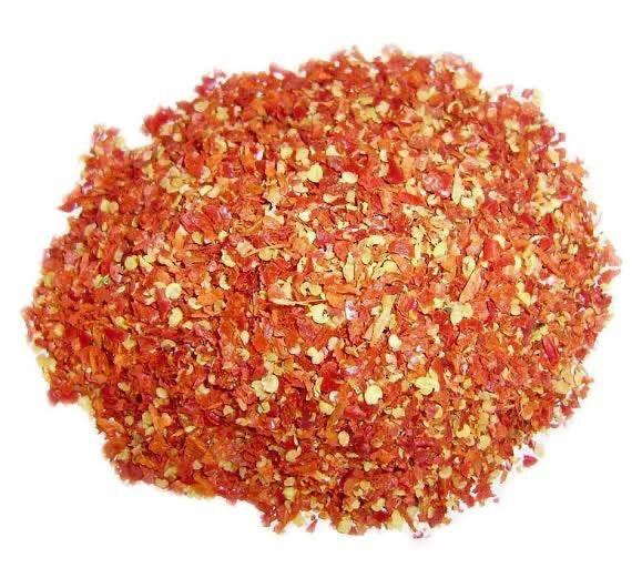 pile of crushed red chili flakes on white background, spicy dried pepper flakes