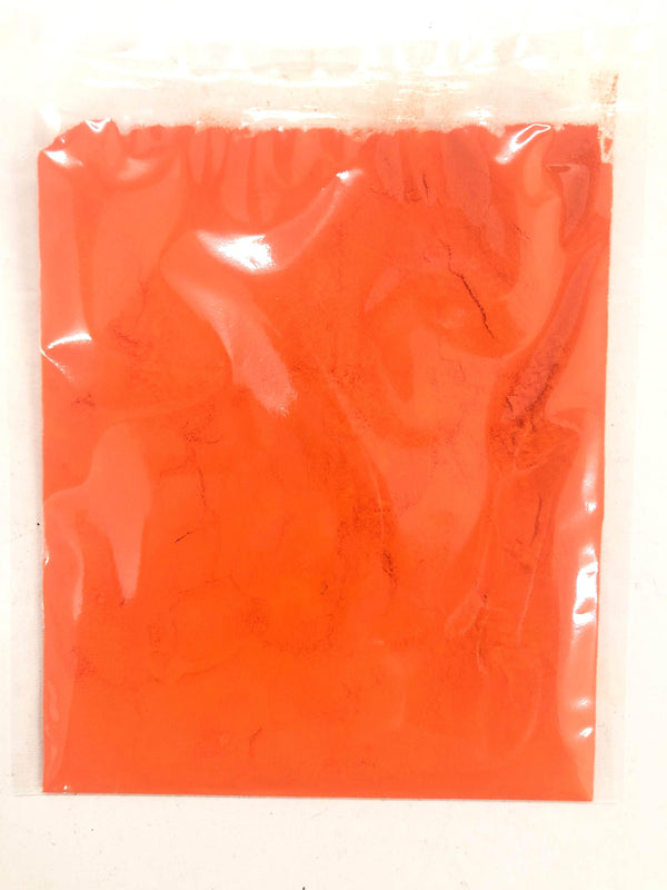 Bright orange powdered pigment in a clear plastic bag on a white background