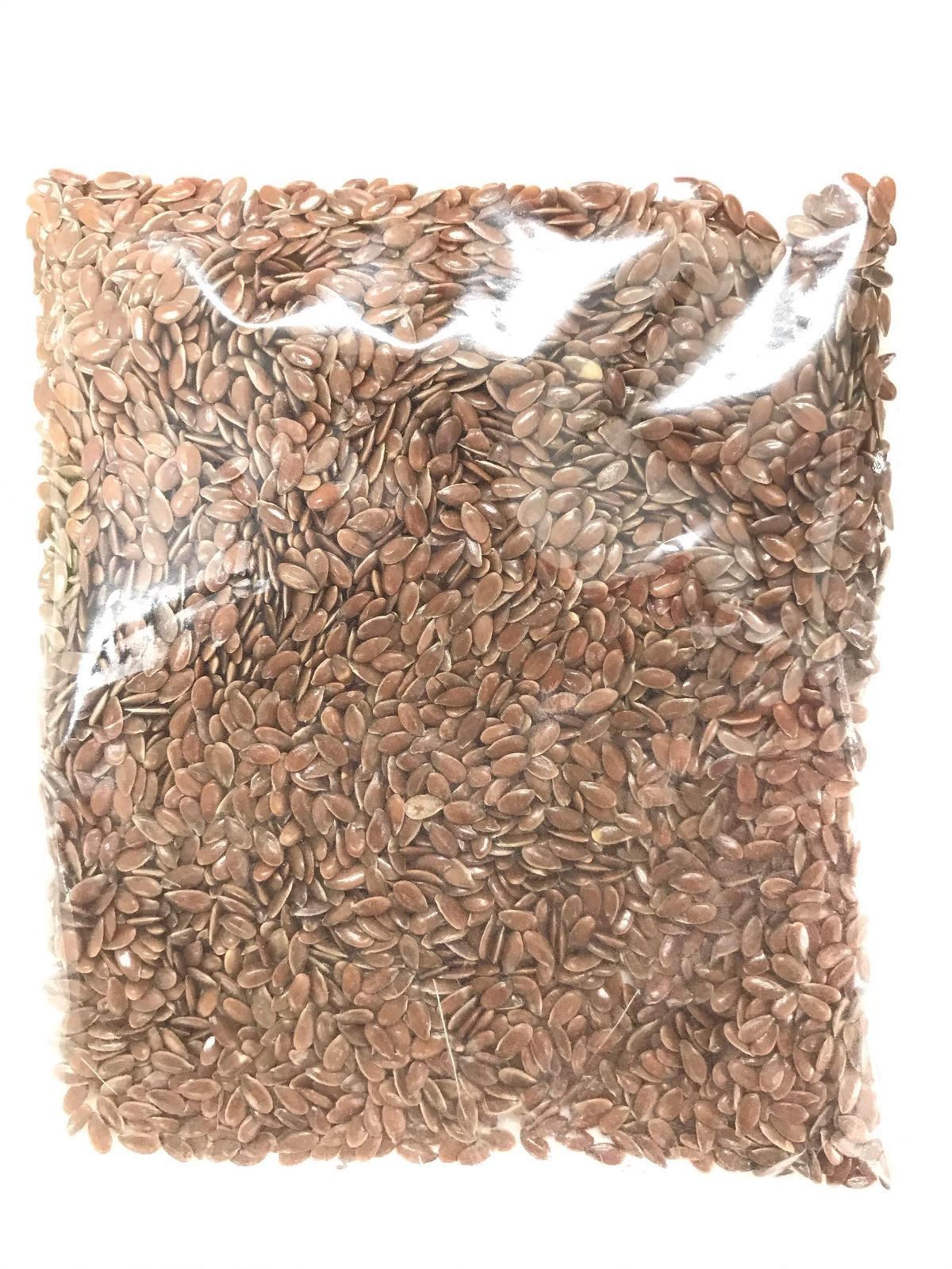 Clear plastic bag filled with brown flax seeds on white background