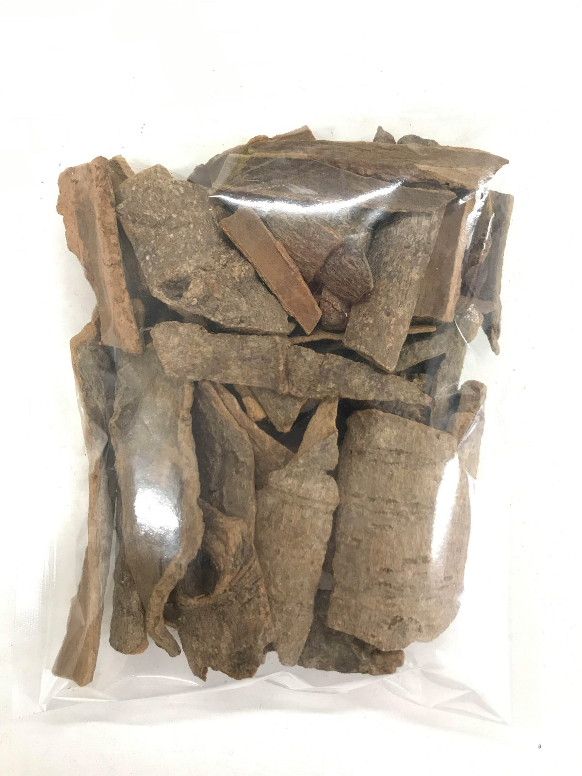 Clear plastic bag filled with large natural cinnamon bark pieces on white background