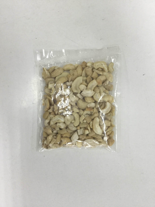 Clear plastic bag filled with mixed broken cashew nuts on a white surface