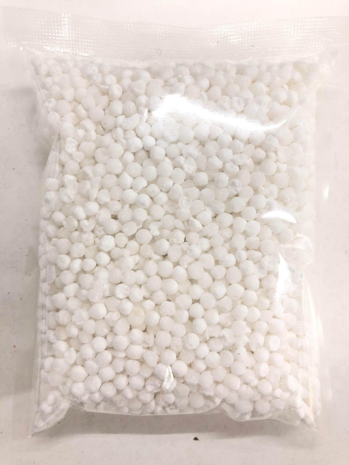 Clear plastic bag filled with small white granules on a light surface