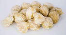 Close-up of peeled, dried nuts or seeds with a light tan color on a white background