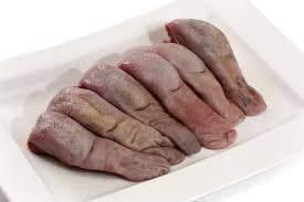 Raw beef tongue slices arranged on a white platter for cooking or grilling