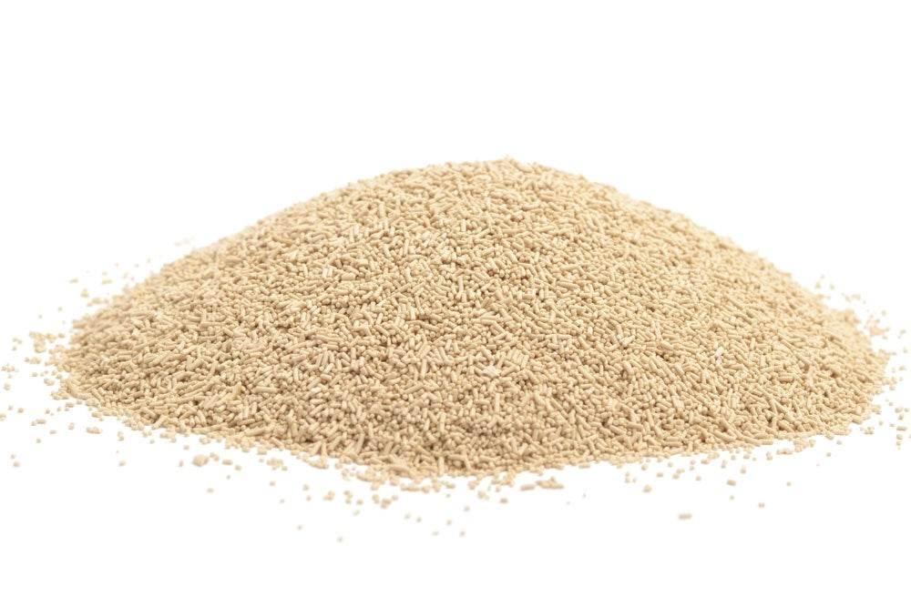 Pile of light beige dry active yeast granules isolated on white background