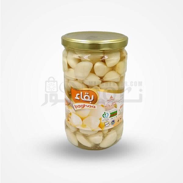 Jar of Baghaa brand whole peeled pickled garlic cloves in clear glass with gold lid