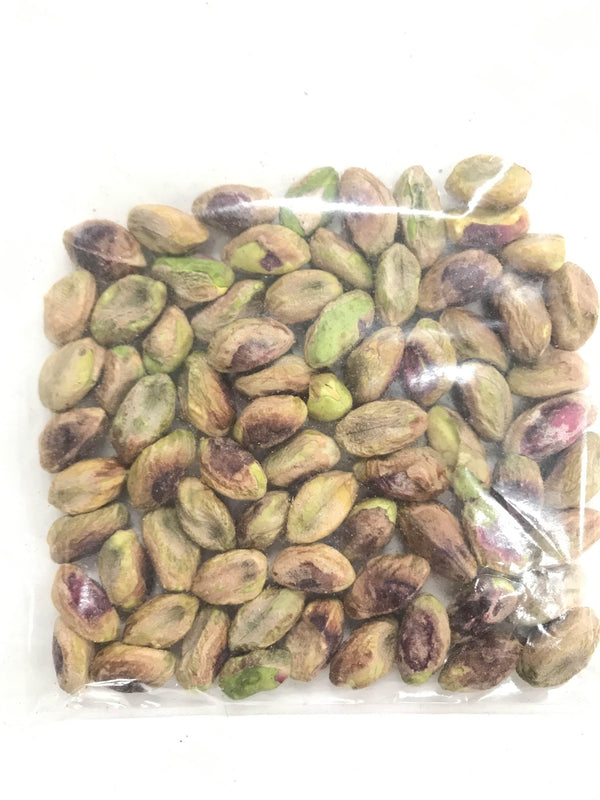 Close-up of shelled pistachio kernels in a clear plastic bag on white background