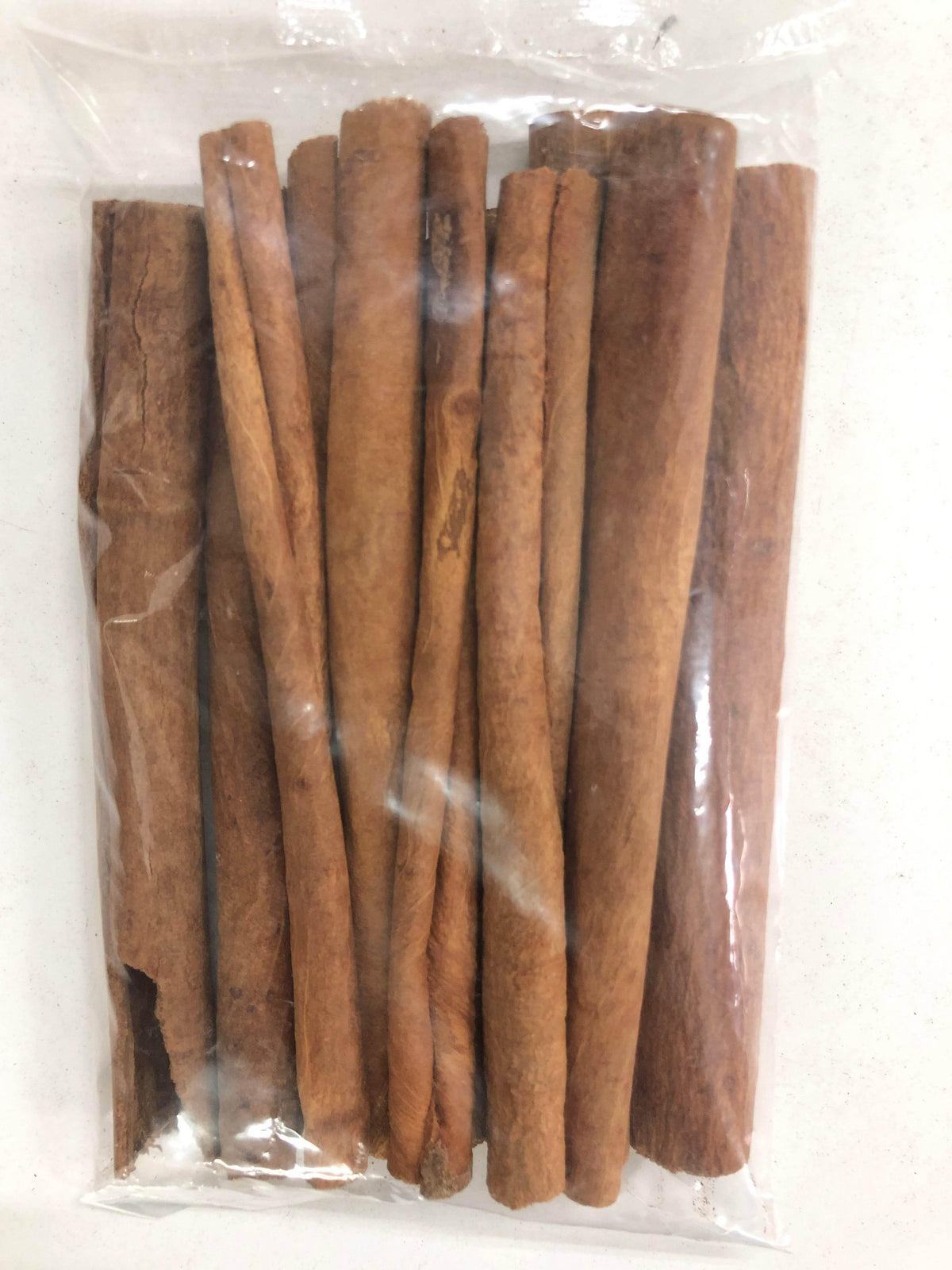 Plastic bag with several brown cinnamon sticks on white background