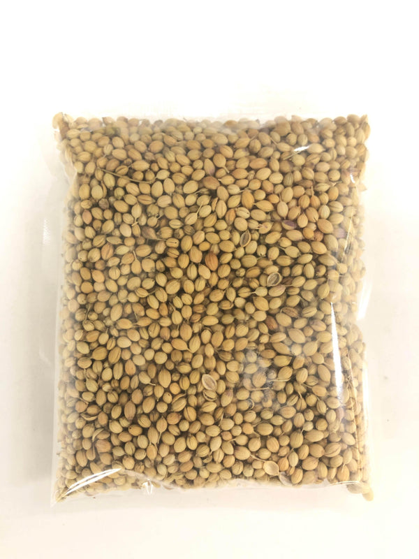 Clear plastic bag filled with light brown coriander seeds on white surface