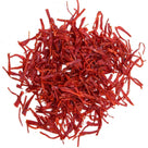 Close-up of vibrant red saffron threads on white background, premium spice strands