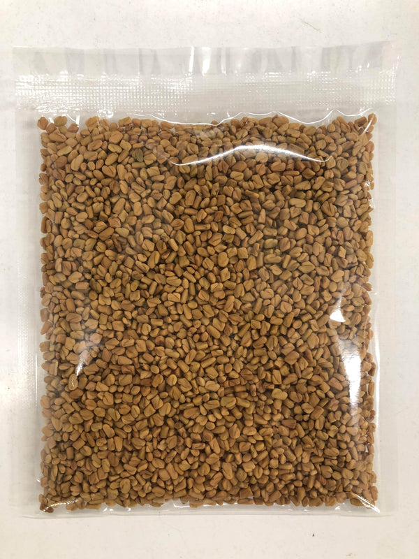 Clear plastic bag filled with small brown fenugreek seeds on a white surface