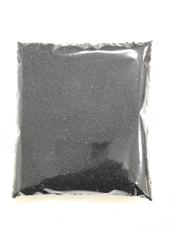 Square transparent plastic bag filled with small black granules on white background