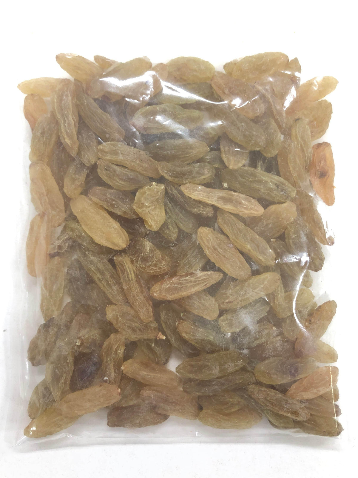 Transparent plastic bag filled with elongated golden brown raisins on white background