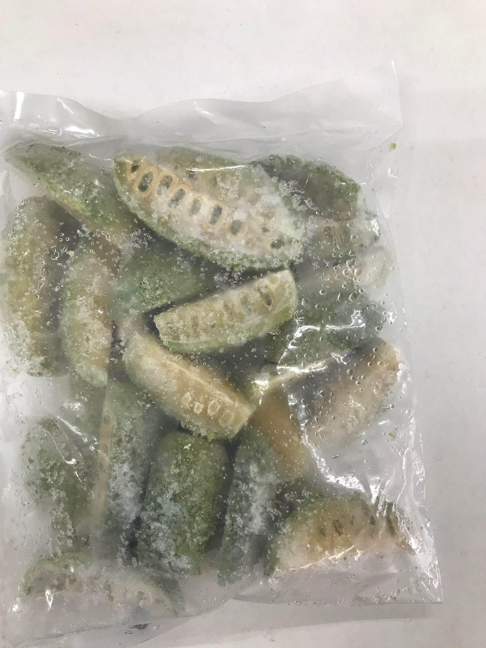 Frozen sliced green bitter melons in a clear plastic vacuum-sealed bag