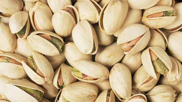 Close-up of shelled pistachio nuts with beige shells and green kernels