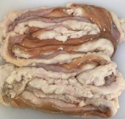 Raw pork intestines with visible fat layers on a white surface, fresh offal for cooking